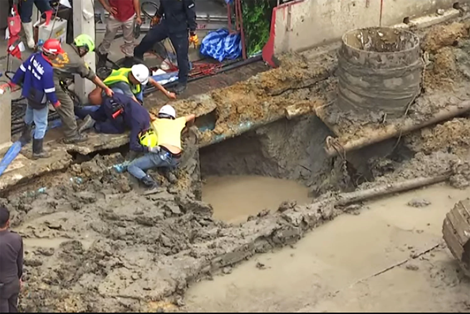 Un travailleur tombe dans un trou profond, enseveli dans le sol et l'eau.